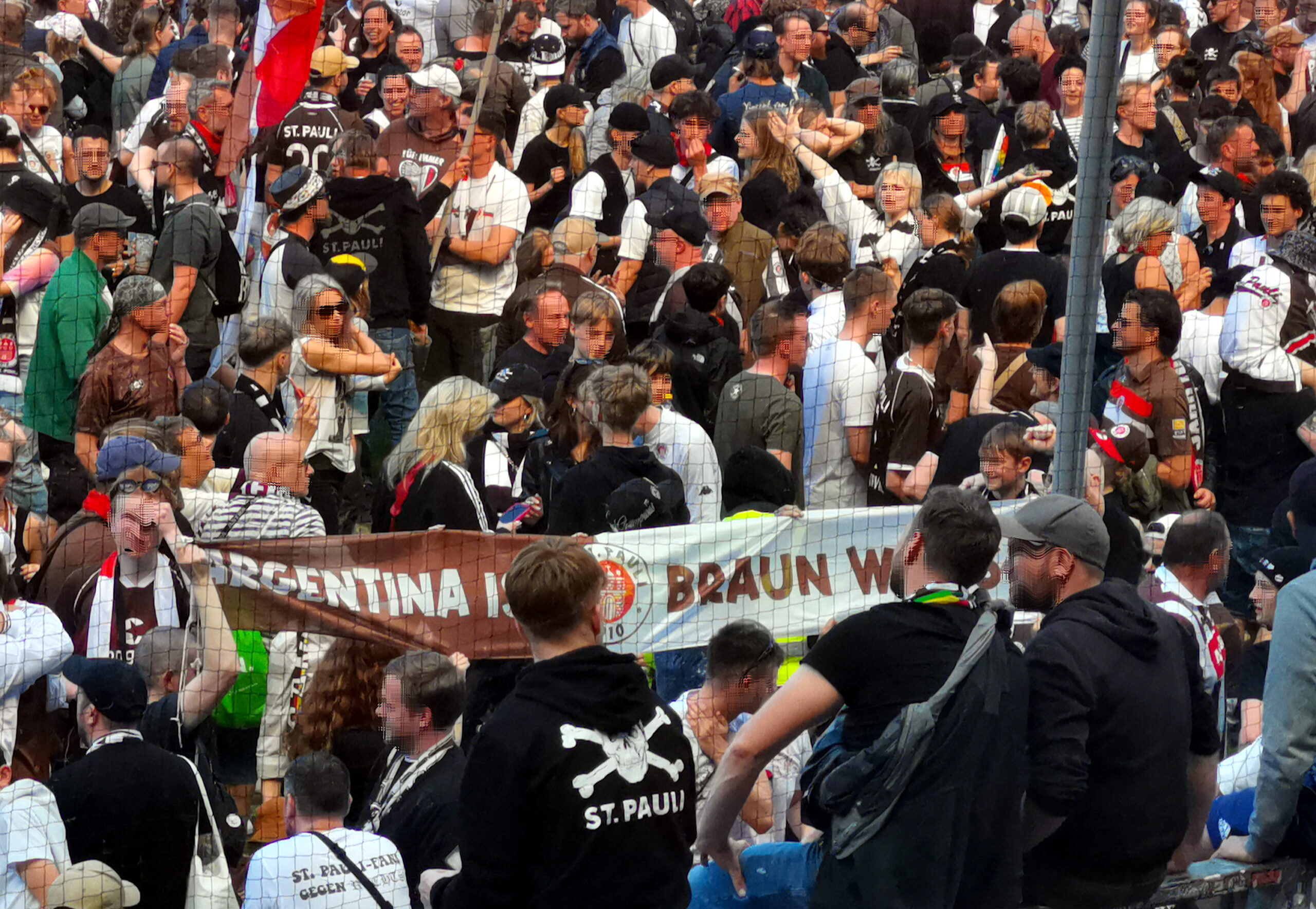 Fans halten in einer Menschentraube auf dem Rasen einen Banner mit Argentinia ist Braun-Weiß - Schriftzug hoch