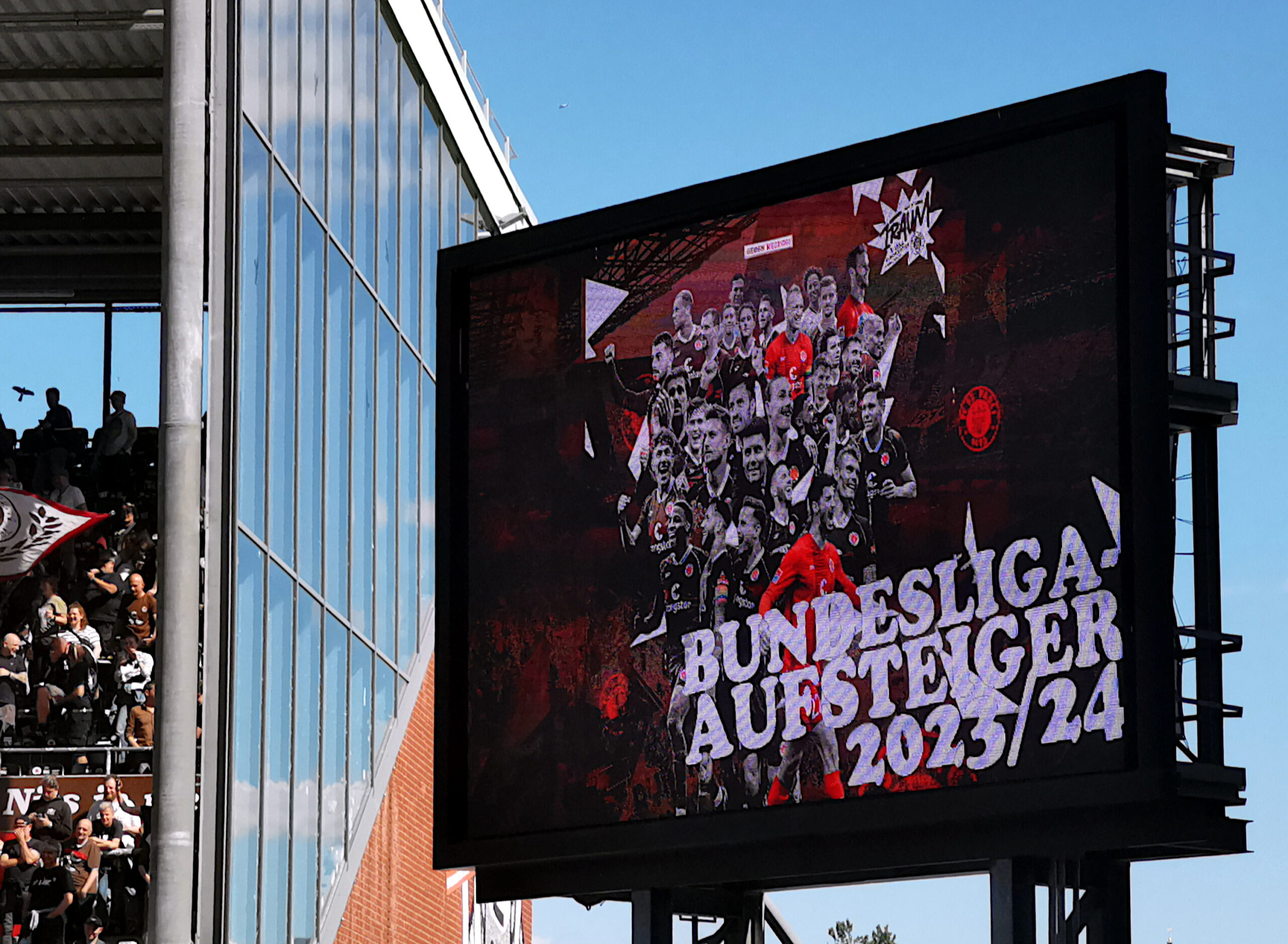 Anzeigetafel im Millerntor-Stadion mit Schriftzug Bundesliga-Aufsteiger 2023-24 und mit jubelnden Spielern